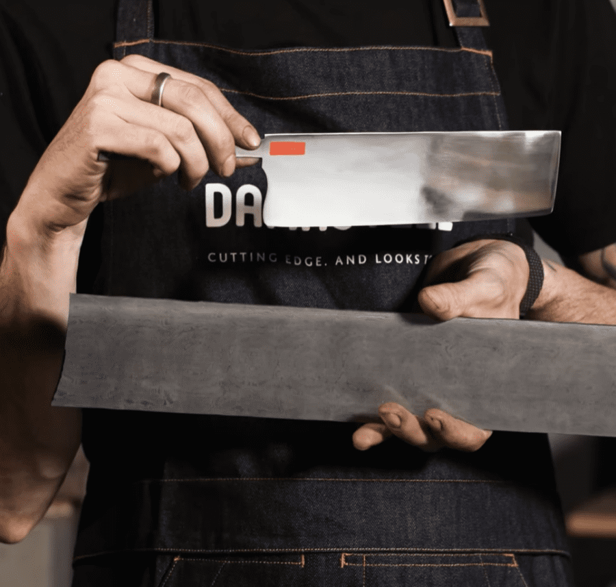 Mans hands showing a raw billet of steel and a highly polished blade shape ready for etching